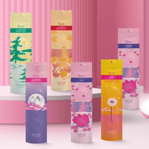 Six different packages of incense sticks standing upright against a hot pink background. From left to right the packages include Sandal-Rose, Cleansing, Coconut, Rose, Bliss, and Jasmine. 