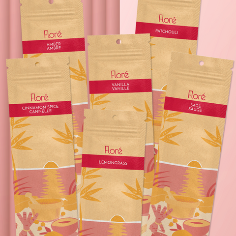 Six different packages of incense sticks lay in two rows against a pale red background. The back row includes Amber, Vanilla and Patchouli, and the front row includes Cinnamon Spice, Lemongrass and Sage.