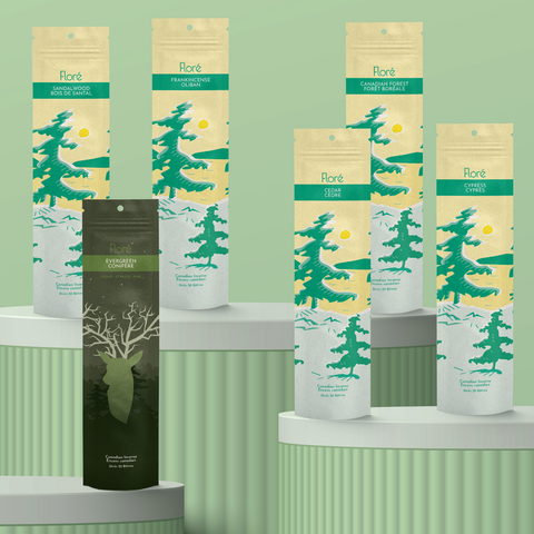 Six different packages of incense sticks standing upright against a mossy green background. From left to right the packages include Sandalwood, Evergreen, Frankincense, Cedar, Canadian Forest, Cypress. 