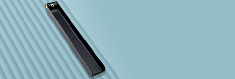 A long black metal incense burner featuring a brass knob at one end that is used to adjust the angle of an incense stick. The burner is sitting on a blue-grey backgound. Designed and fabricated by Toronto CNC machine shop Rocket Surgery Solutions.