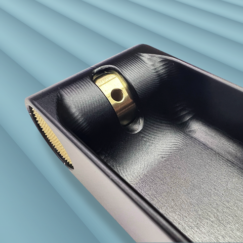 A close up of the end of a black metal incense burner that contains a brass knob with a hole to hold an incense stick against a blue-grey background. The brass knob can be turned to adjust the angle of the incense stick. Designed and fabricated by Toronto CNC machine shop Rocket Surgery Solutions. 