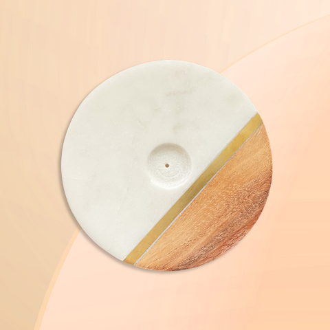 Overhead view of a round flat disk incense burner featuring the moon cycle around the image of a goddess against a grey background. 