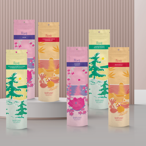 Six different packages of incense sticks standing upright against a pale burgundy pink background. From left to right the packages include Frankincense and Myrrh, Rose, Cinnamon Spice, Jasmine, Sandalwood and Patchouli.