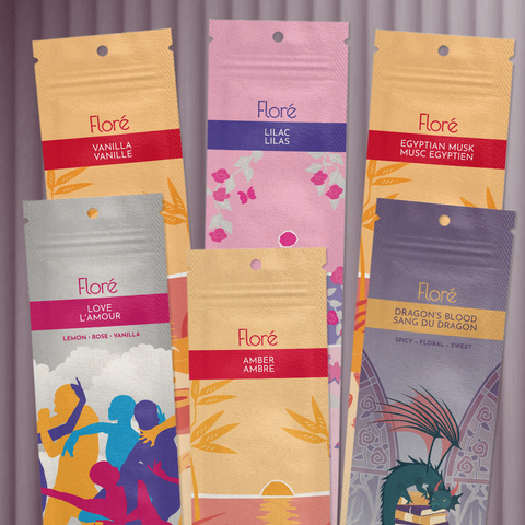 Six different packages of incense sticks lay in two rows against a pale grey background. The back row includes Vanilla, Lilac, Egyptian Musk, and the front row includes Love, Amber and Dragon's Blood.
