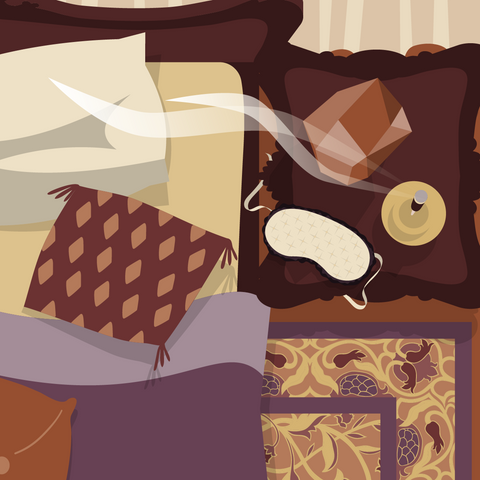 Overhead illustrated view of a lusciously adorned bedroom showing the corner of a cozy bed with throw pillows next to a night stand containing a salt rock lamp, sleep mask, and burning stick of incense. An ornate rug is visible next to the bed. 