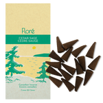 Image of Flore Canadian Incense Cedar-Sage package, featuring green pine trees on a golden lake with a yellow sun. There are 20 incense cones splayed beside it as every package contains 20 incense cones. 
