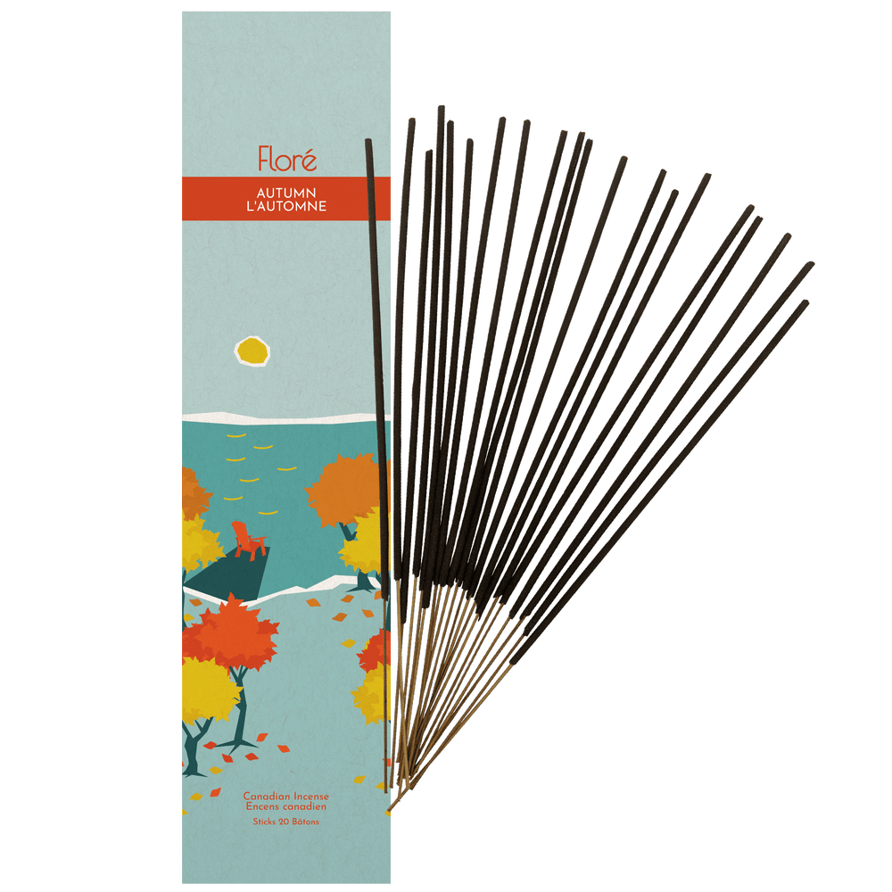 Image of Flore Canadian Incense Autumn package, featuring fall colour maple trees on a blue lake with a yellow sun. There is a dock with a muskoka chair. There are 20 incense sticks splayed beside it as every package contains 20 incense sticks. 
